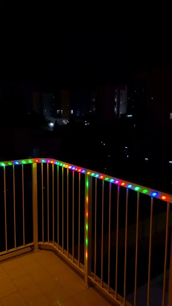 Colorful LED strip lights attached to balcony railings at night