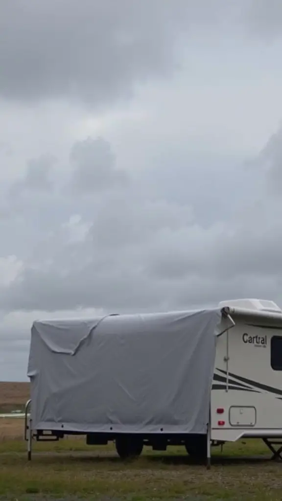 15+ Stylish RV Covers with Deck Designs to Elevate Your Outdoor Space 11 An RV covered with a protective cover, set against a cloudy sky.