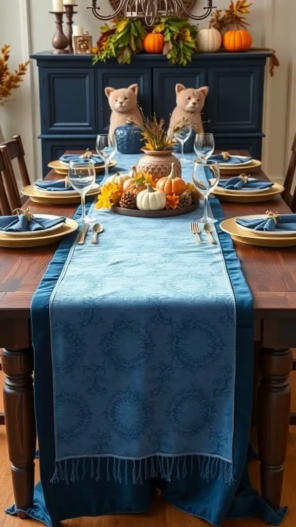 A beautifully set Thanksgiving table featuring a blue velvet table runner, pumpkins, and decorative elements.
