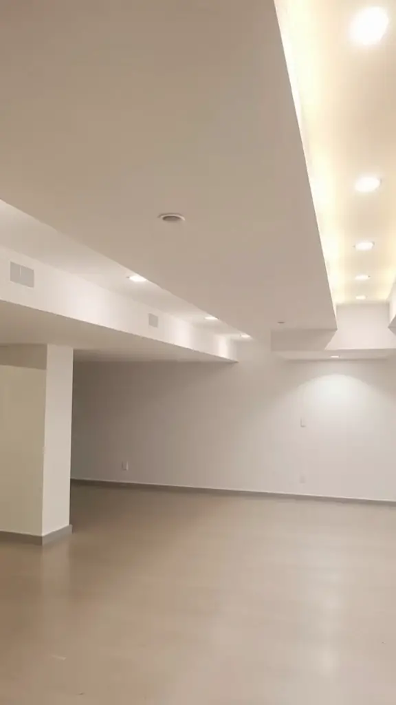 A modern basement with recessed lighting in the ceiling, showcasing a sleek and clean design.