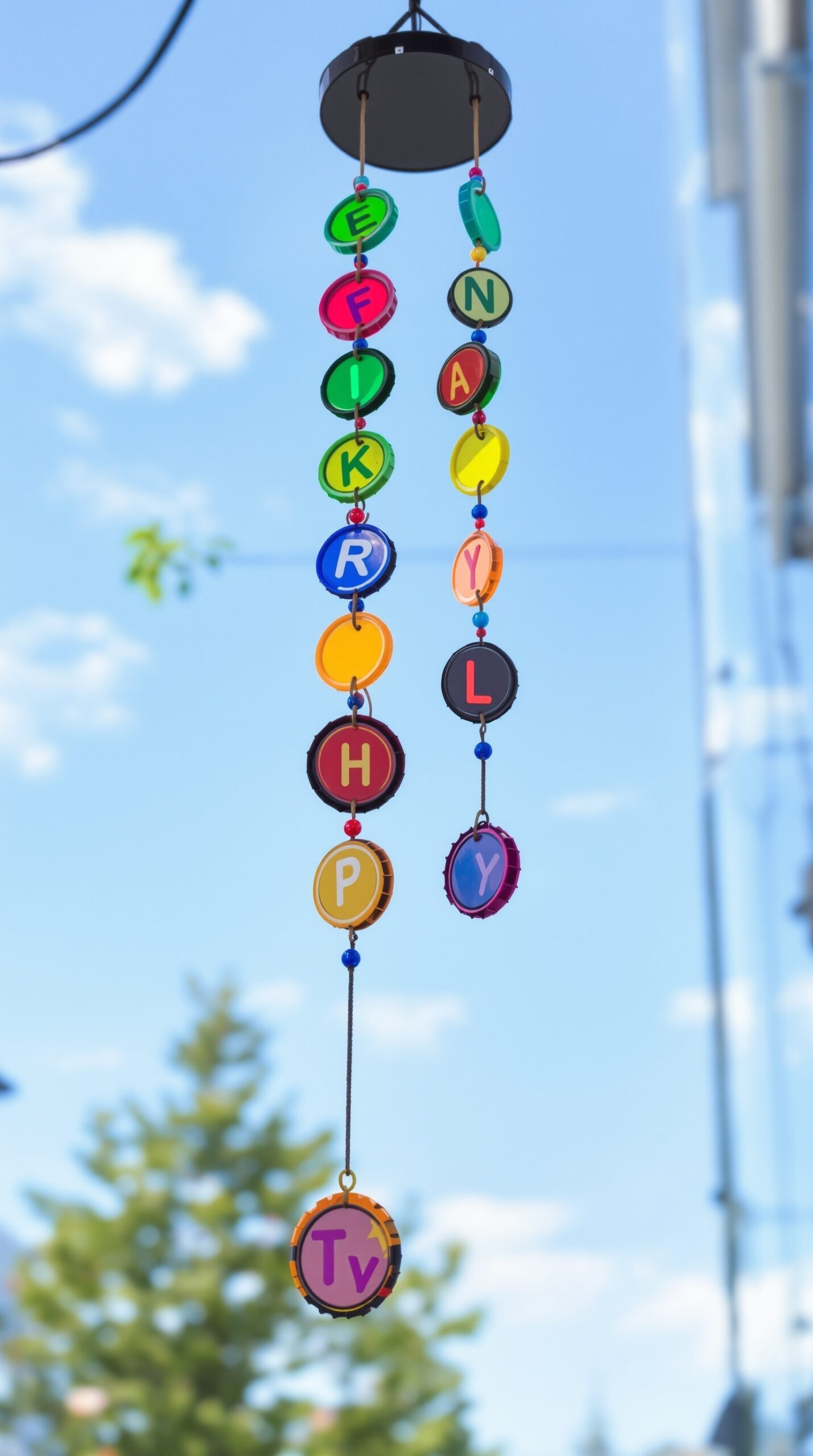 27+ DIY Wind Chime Ideas You Can Make on a Budget (Beautiful & Easy Projects) 10 Colorful bottle cap wind chimes hanging against a blue sky