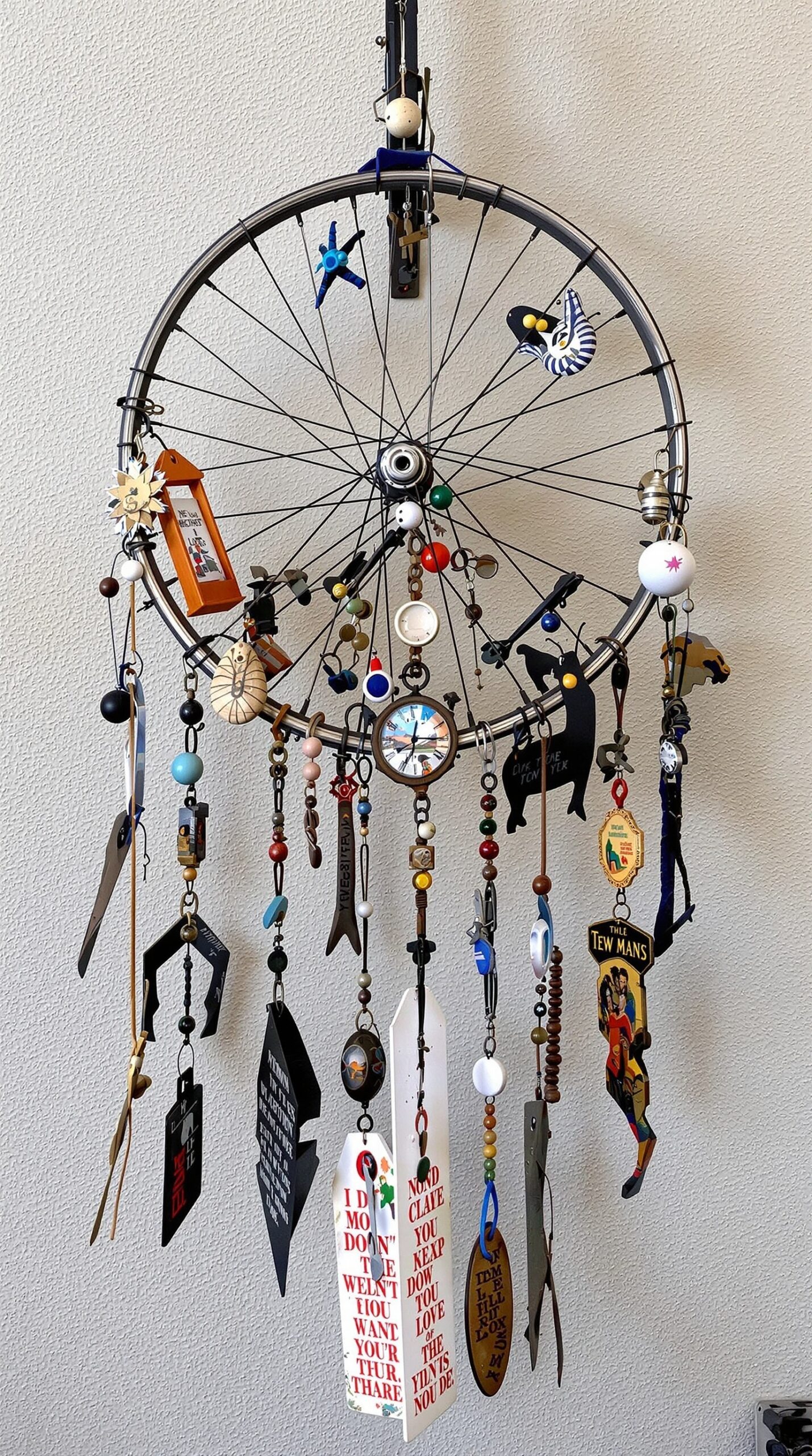 27+ DIY Wind Chime Ideas You Can Make on a Budget (Beautiful & Easy Projects) 11 A colorful bicycle wheel wind chime with various trinkets hanging from it.