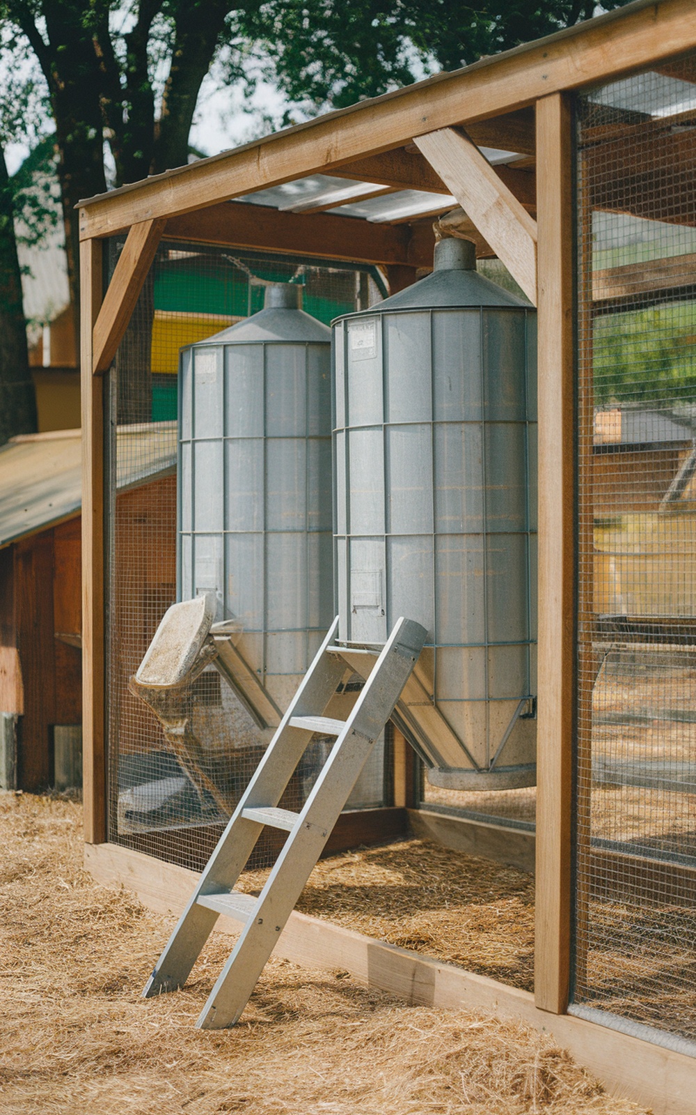 17+ Chicken Coop With Storage Ideas for a More Organized Backyard 12 Two large metal feed storage bins under a wooden shelter in a chicken coop