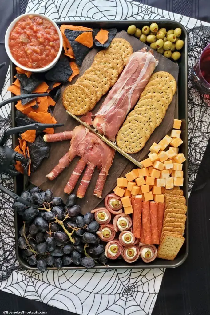 39 Spooky Charcuterie Board Ideas For Your Next Halloween Party 7 Creepy prosciutto hand charcuterie board with crackers, cheese, olives, grapes, meat, chips, and salsa