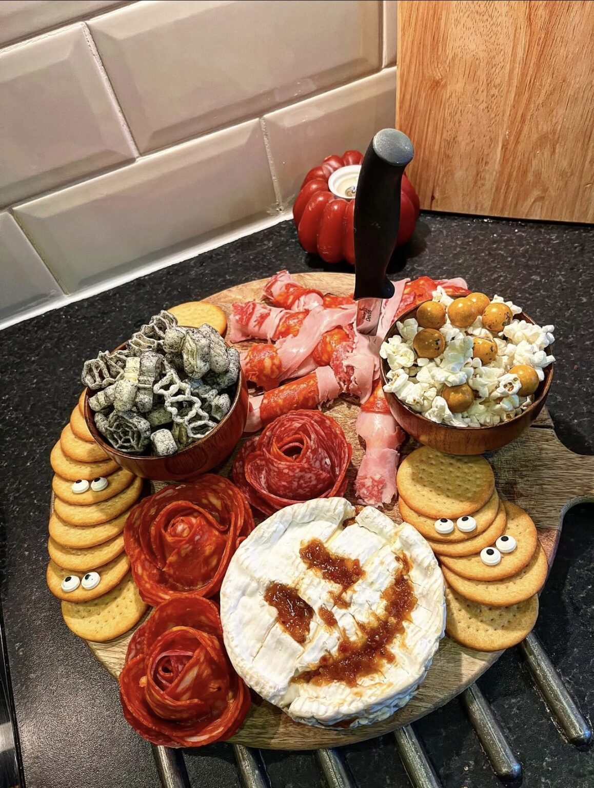 39 Spooky Charcuterie Board Ideas For Your Next Halloween Party 10 Creepy knife Halloween snack board with baked brie, salami roses, crackers, popcorn, and wrapped meats
