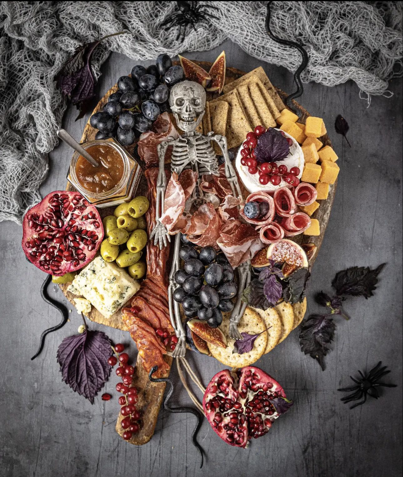 39 Spooky Charcuterie Board Ideas For Your Next Halloween Party 12 Rustic skeleton harvest charcuterie board with grapes, pomegranate, figs, olives, cheese, crackers, and meats
