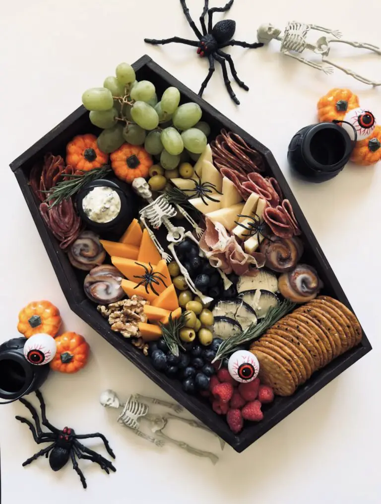 39 Spooky Charcuterie Board Ideas For Your Next Halloween Party 13 Coffin Halloween charcuterie board with cheese, crackers, meat, grapes, olives, berries, and skeleton decorations