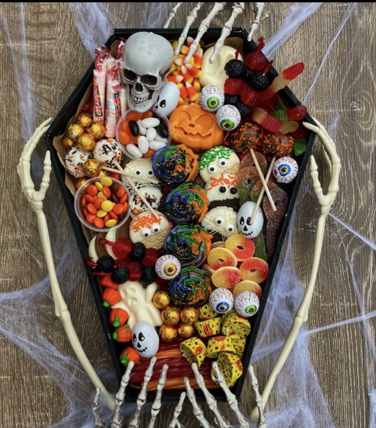 41 Spooky Dessert Board Ideas for Halloween Parties 4 Coffin shaped Halloween dessert board filled with cookies, candies, cake pops, and eyeball sweets