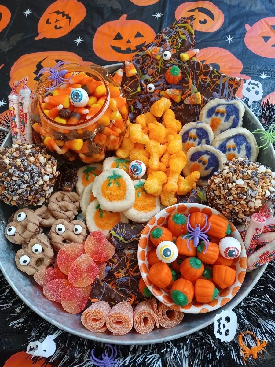 41 Spooky Dessert Board Ideas for Halloween Parties 9 Halloween dessert platter with pumpkin cookies, ghost cookies, candy pumpkins, chocolate bark, and caramel apples
