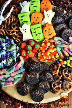 41 Spooky Dessert Board Ideas for Halloween Parties 11 Halloween dessert board with decorated marshmallows, chocolate cookies, candy corn, gummy worms, and pretzels