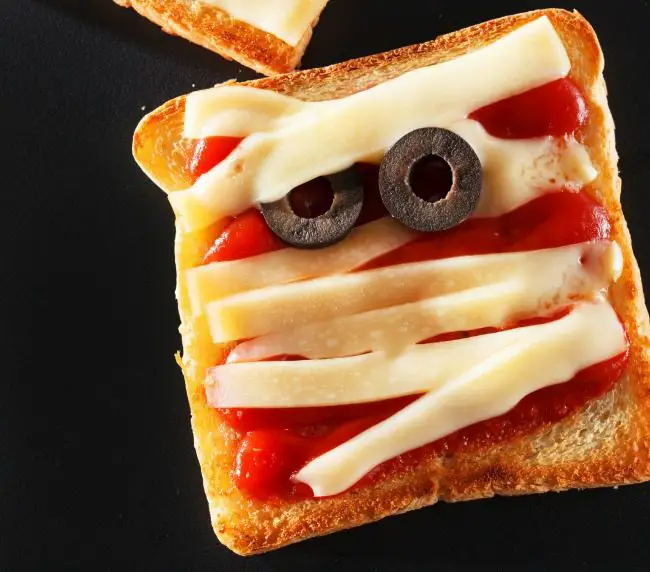 27 Halloween Treats for Kids and Adults That Everyone Will Love 15 Mummy pizza toast with cheese strips and black olive eyes
