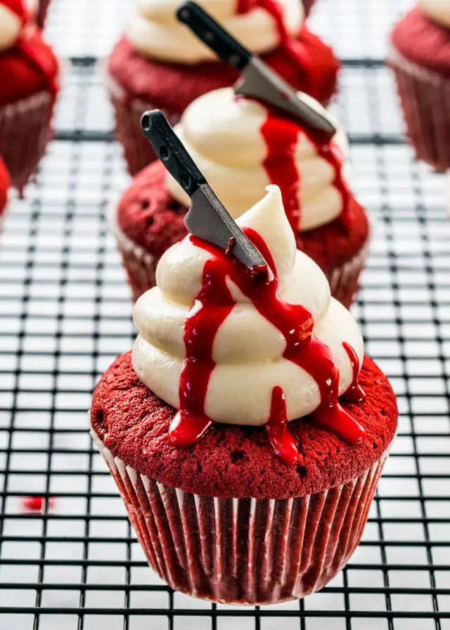 27 Halloween Treats for Kids and Adults That Everyone Will Love 16 Red velvet Halloween cupcakes with bloody frosting and toy knives