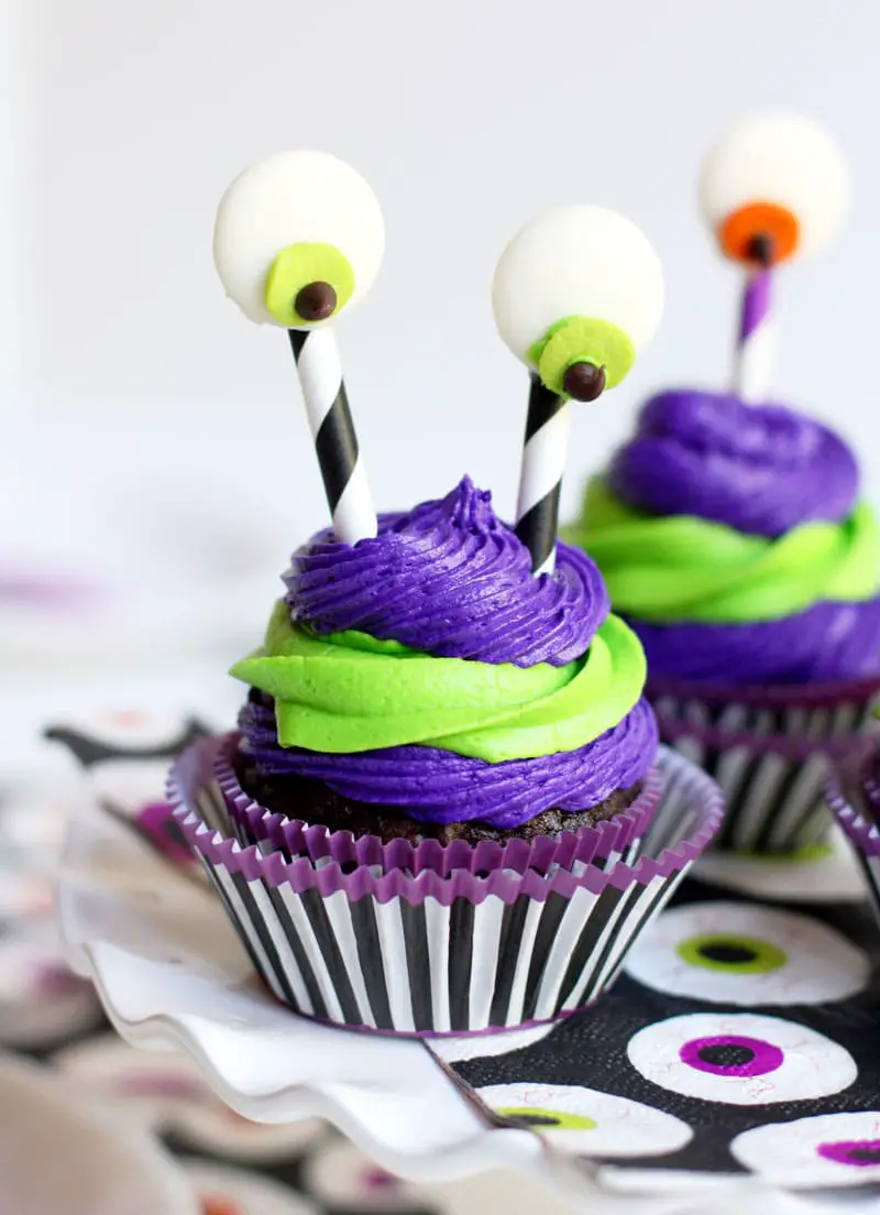 27 Halloween Treats for Kids and Adults That Everyone Will Love 19 Purple and green monster cupcakes with tall candy eyeballs