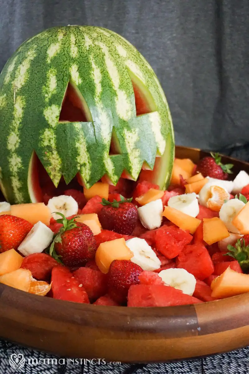 27 Halloween Treats for Kids and Adults That Everyone Will Love 22 Carved jack o lantern watermelon surrounded by fresh fruit
