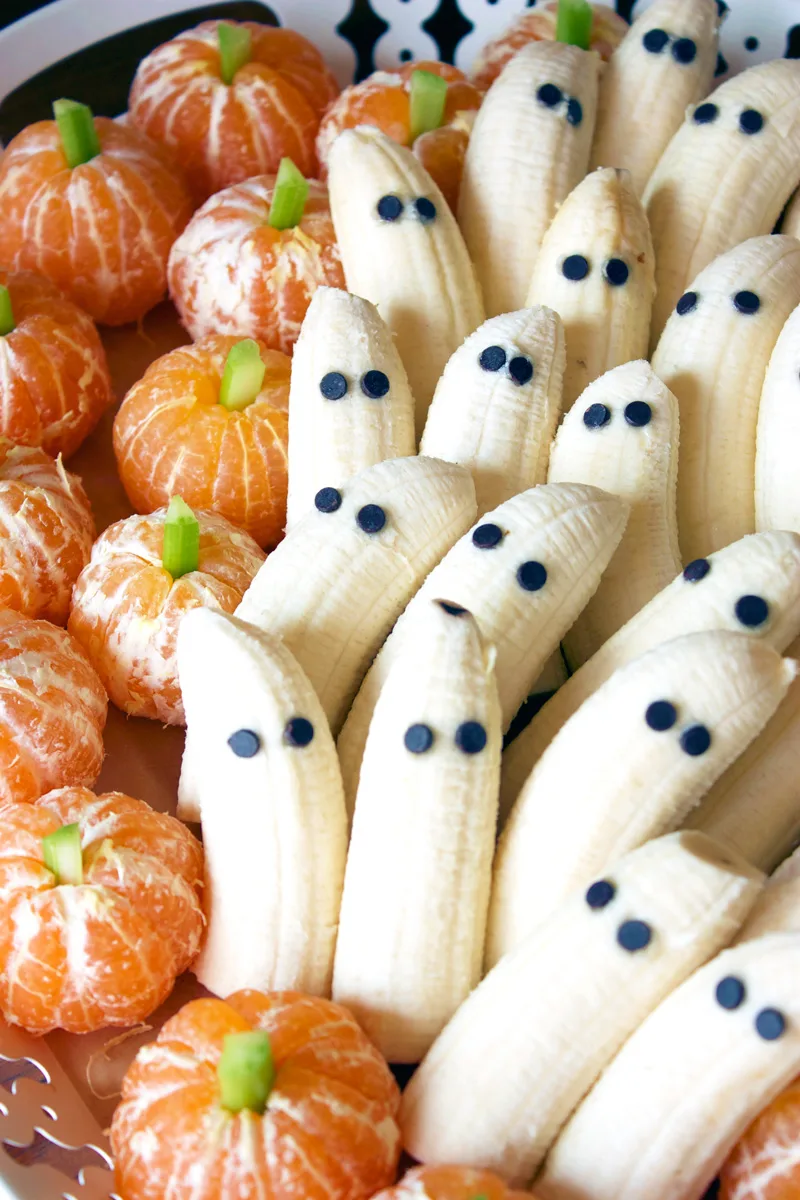 27 Halloween Treats for Kids and Adults That Everyone Will Love 28 Banana ghosts and clementine pumpkins arranged on a platter
