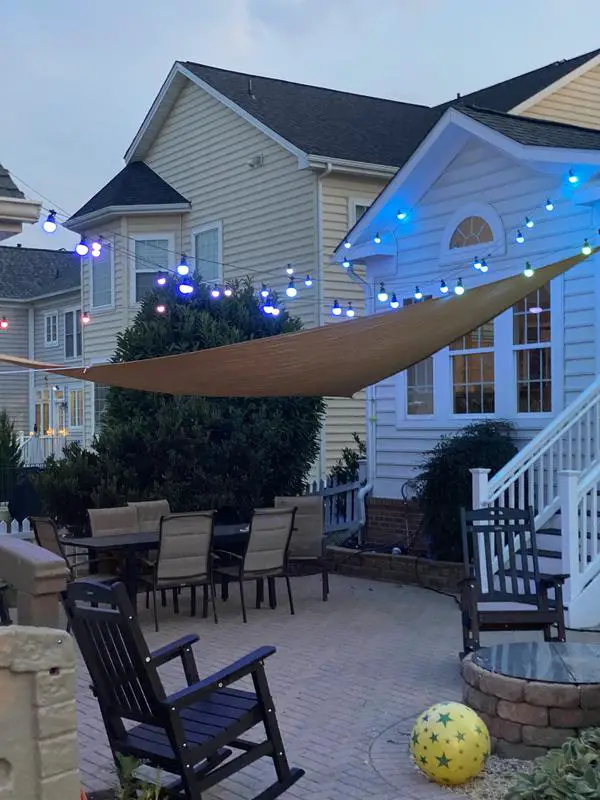 31+ Outdoor String Lighting Ideas for a Cozy and Beautiful Backyard 2 Colored globe string lights above a sun shade sail on an outdoor patio