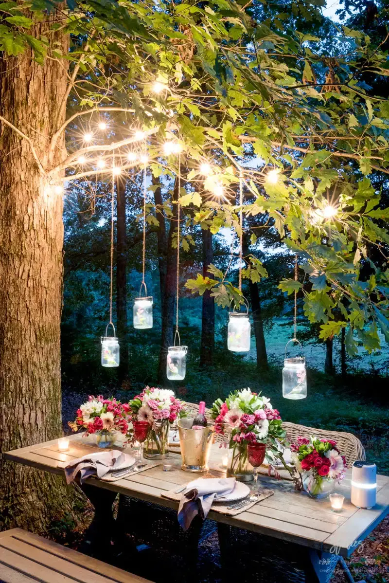 31+ Outdoor String Lighting Ideas for a Cozy and Beautiful Backyard 10 Mason jar lights hanging from tree branches above a rustic dining table