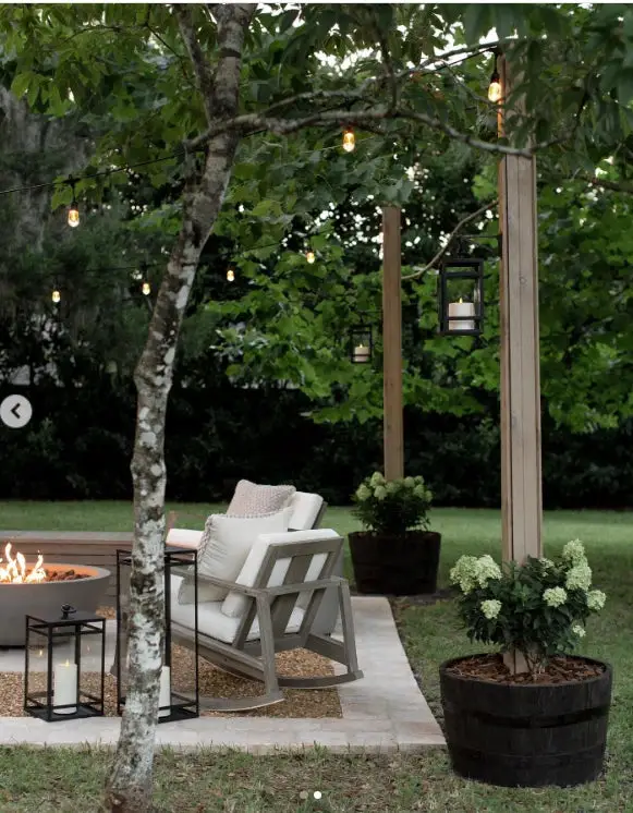 31+ Outdoor String Lighting Ideas for a Cozy and Beautiful Backyard 17 Stone fire pit patio with string lights supported by wooden planter posts